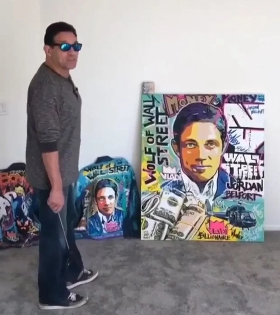 Jordan Belfort standing next to colorful Wolf of Wall Street pop art portrait and branded merchandise